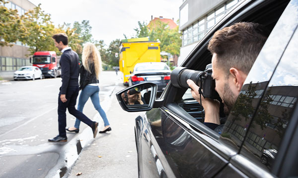 Private investigator taking a picture of a male and female from a car
