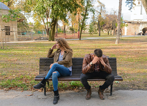 Male and female couple in a dispute on a bench in a park
