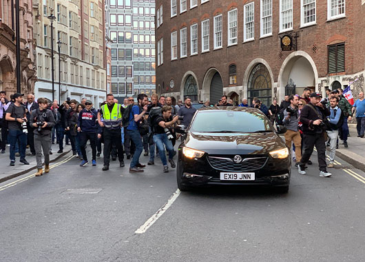 Crowed on people surrounding a black car on a street